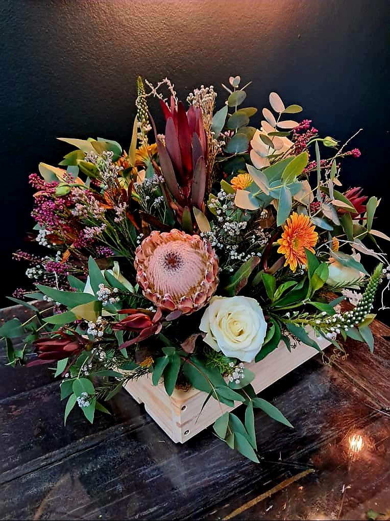 Protea and rose arrangement in wooden box
